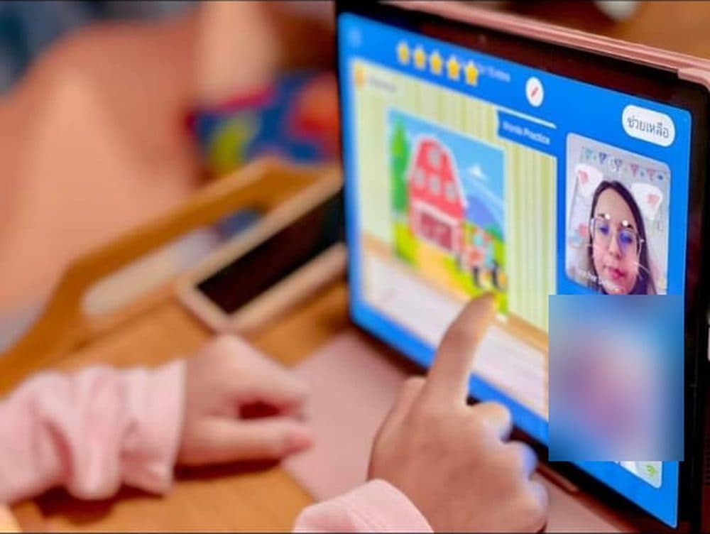 A young student pointing at a tablet during an online lesson with Debora